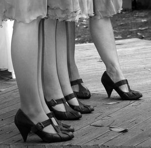 A row of women standing in a line, the view is cropped to show only legs.