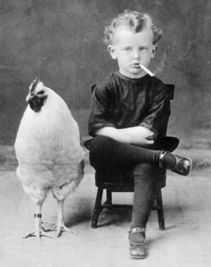 Boy smoking sitting next to a chicken