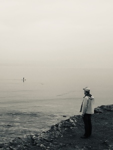 A man standing on a cliff looking out at the water