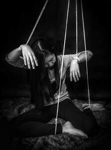 Woman with string tied to her limbs like a marionette