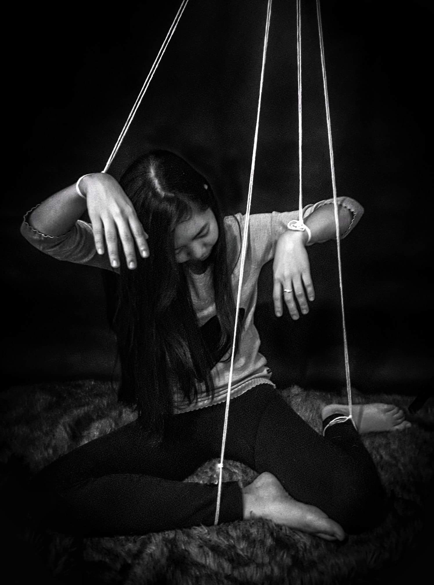 Woman with string tied to her limbs like a marionette 