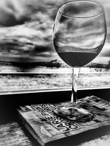 Wine glass resting on a book in a window.