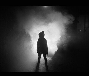 a figure standing in silhouette in a frosty dark
