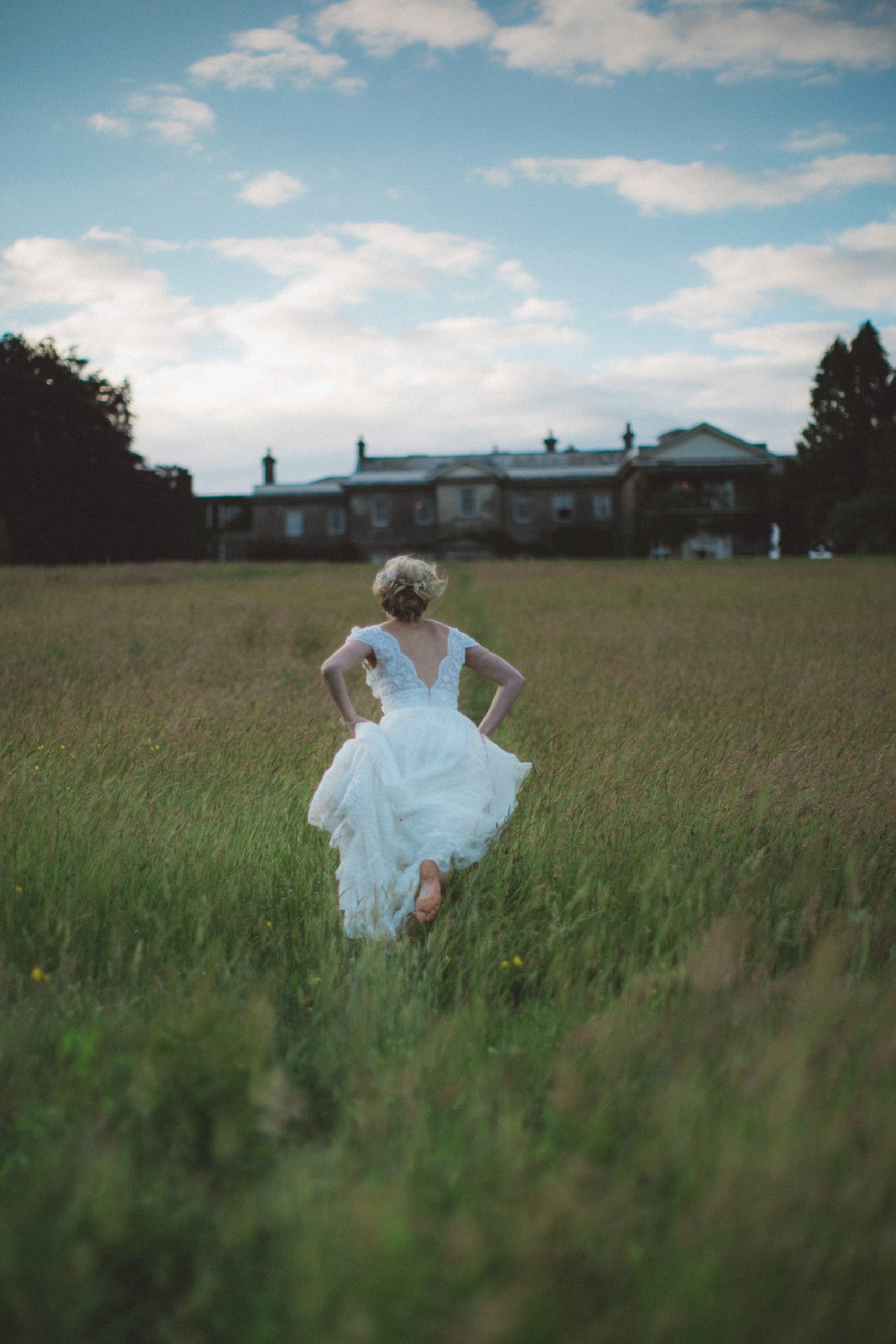 Bride running through a field towards a church