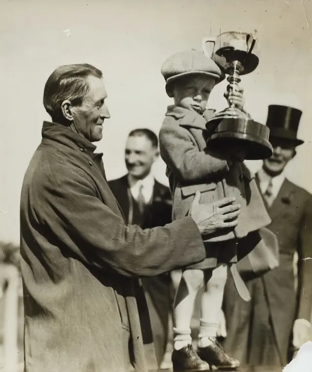 Man holding a little boy holding a trophy