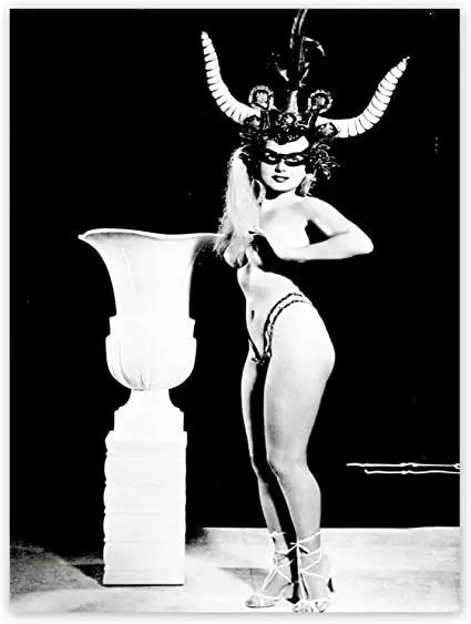 Vintage burlesque dancer wearing horns standing next to a vase
