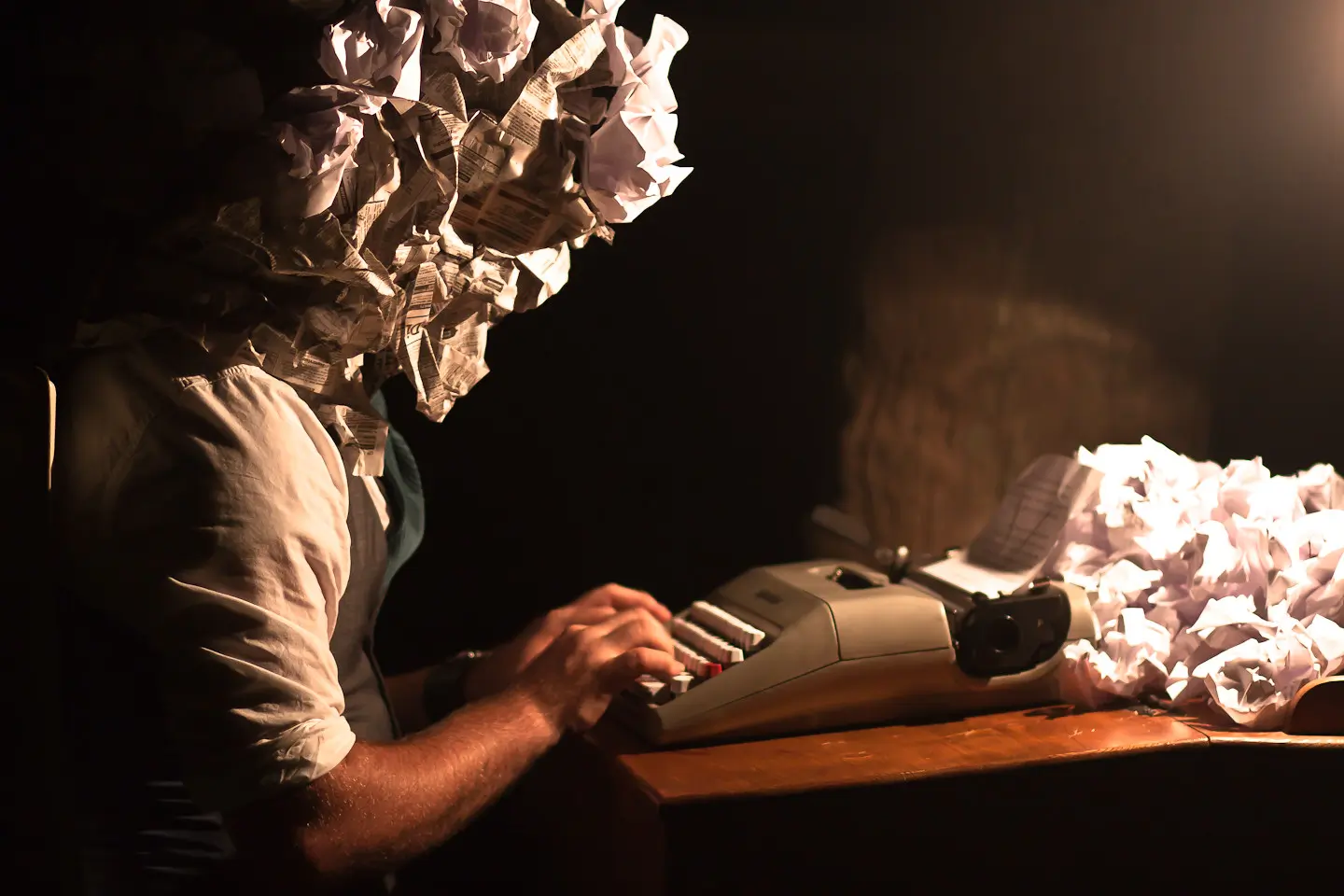 Man working at a typewriter with wadded up paper for a head