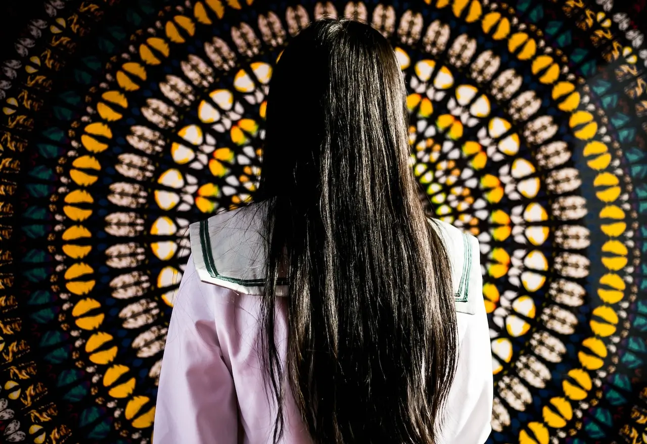 a woman with long hair facing a tapestry