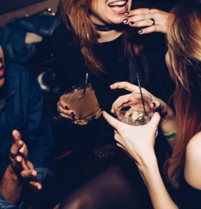 Two young women talking at a party holding cocktails