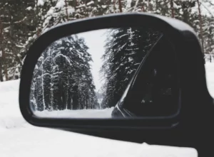 Someone looking through their side mirrors at a winter scene