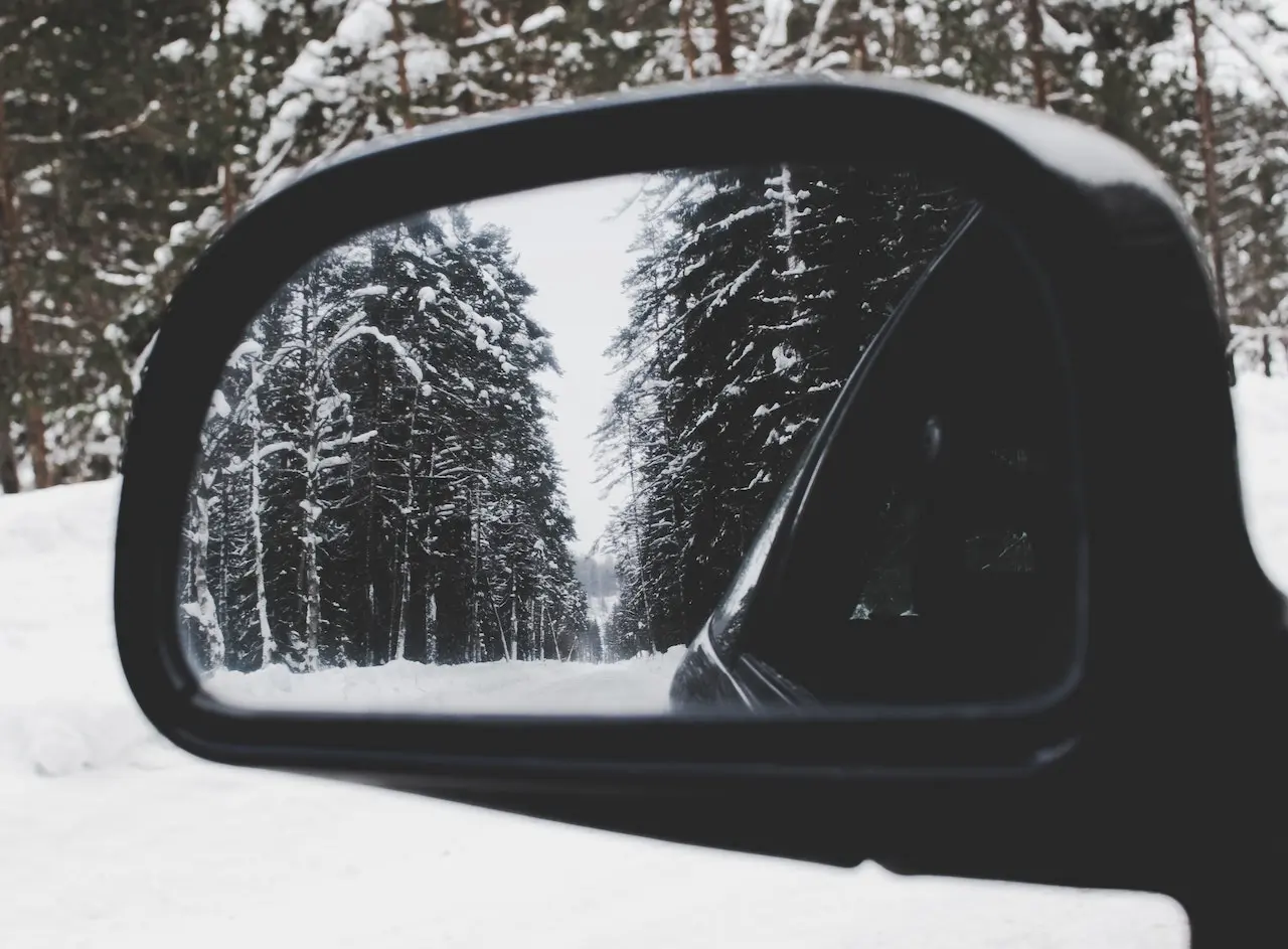 Someone looking through their side mirrors at a winter scene