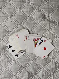 Deck of cards spread out on an unmade bed.
