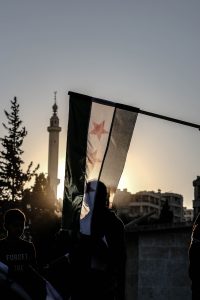 Men in a City and Syrian Flag