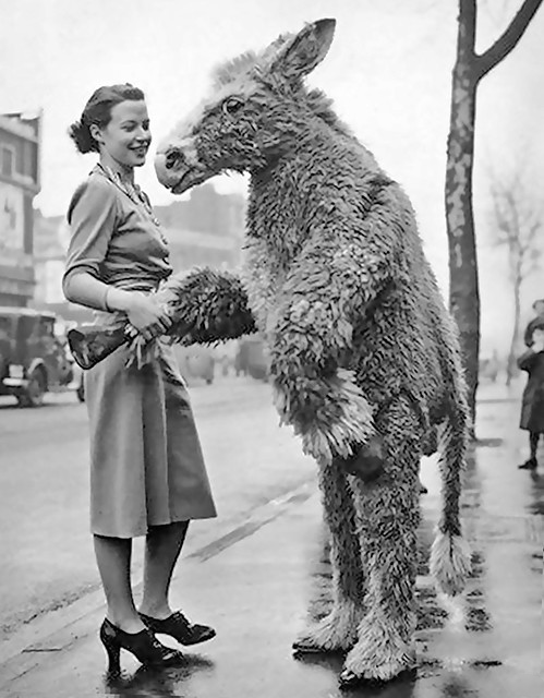 Vintage photo of a woman shaking hands with a person in a giant donkey costume