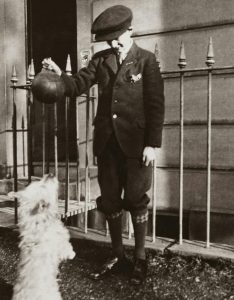 grayscale photography of boy playing ball with the dog