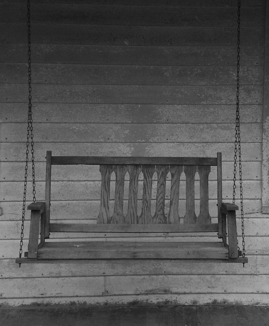 Black and white photo of an old porch swing