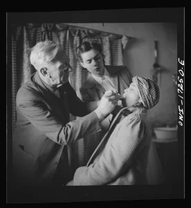 Country doctor examining a woman while her husband watches