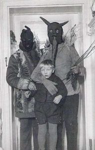 Vintage photo of two people in bizarre costumes clutching a scared boy