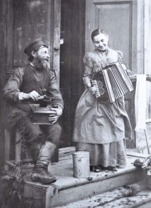 Vintage photo of a man with a coffee grinder and a woman with an accordion.