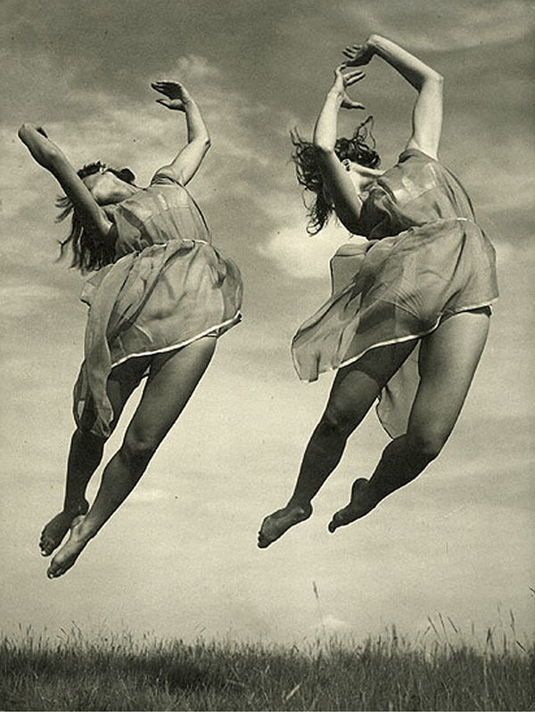 Photo of two women in summer dresses leaping into the air