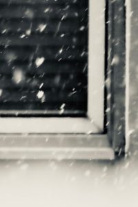 Outdoor photo of a windowsill with snow falling