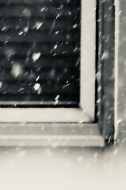 Outdoor photo of a windowsill with snow falling